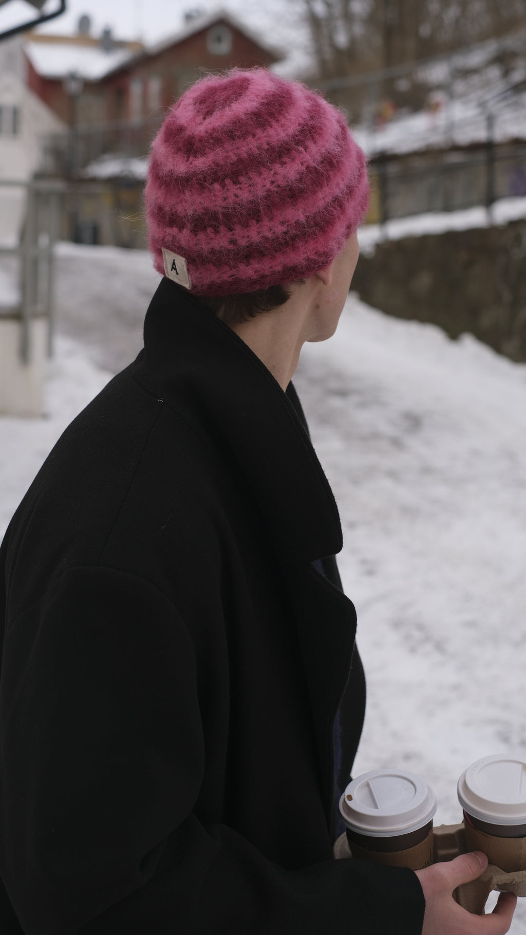 Person wearing a black coat and pink knit hat in a snowy outdoor setting