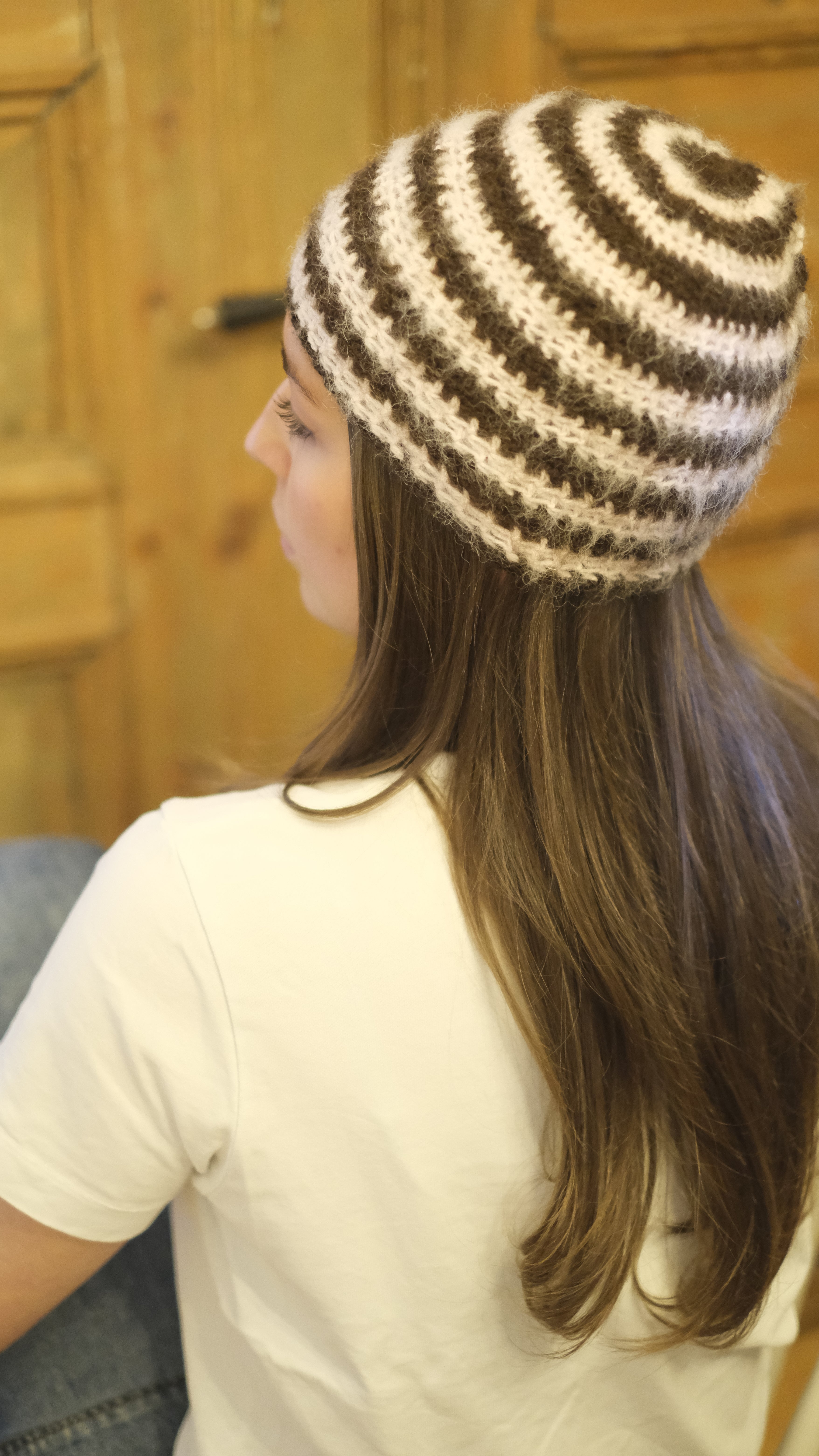 Person wearing a striped beanie with a wooden surface in the background