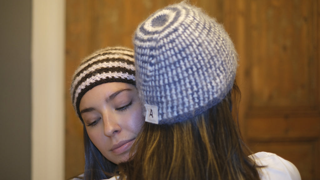 Two people wearing knitted hats with a wooden door in the background