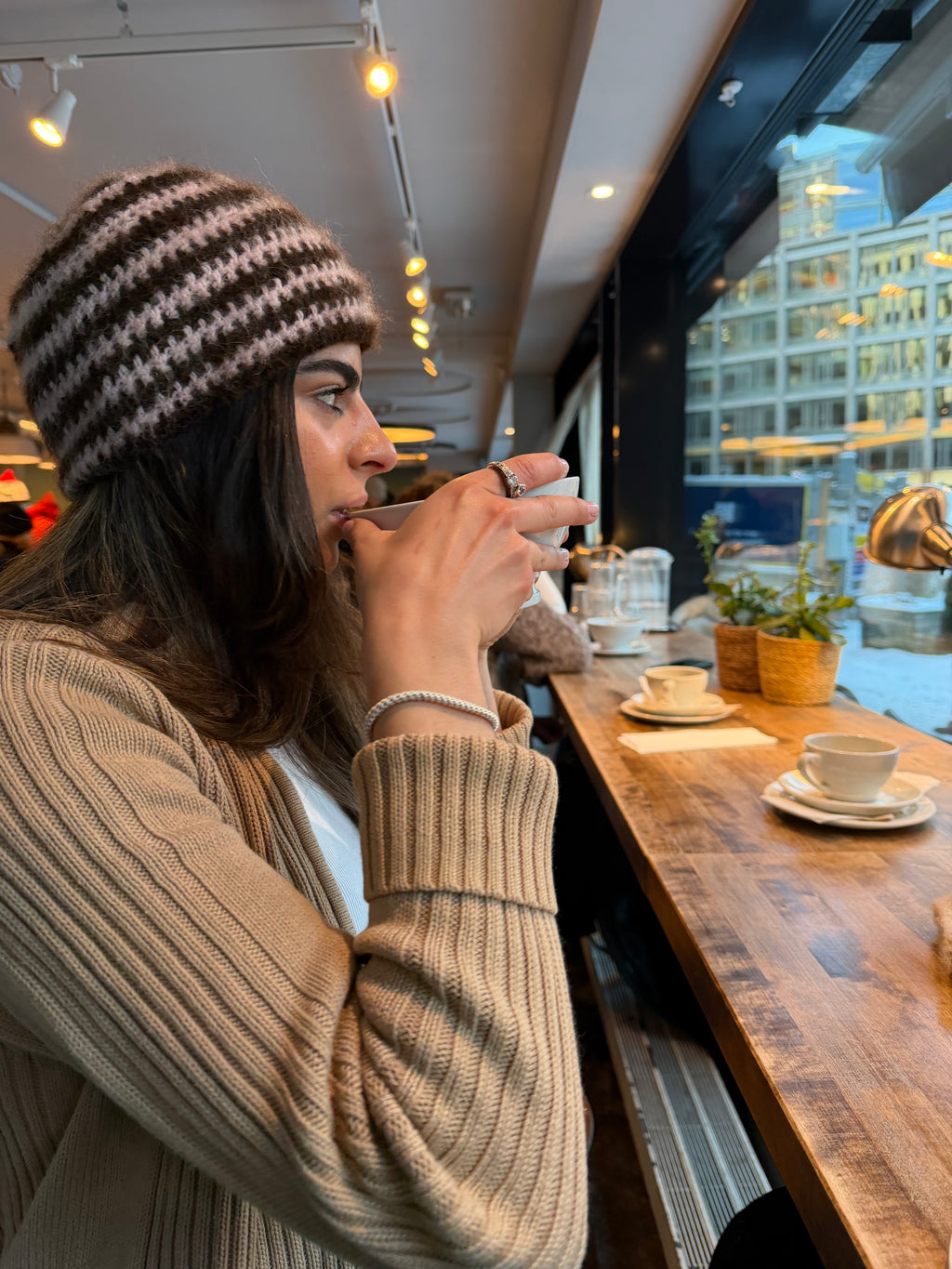 Woman drinking from a coffee cup in a cafe with a cityscape view in Oslo